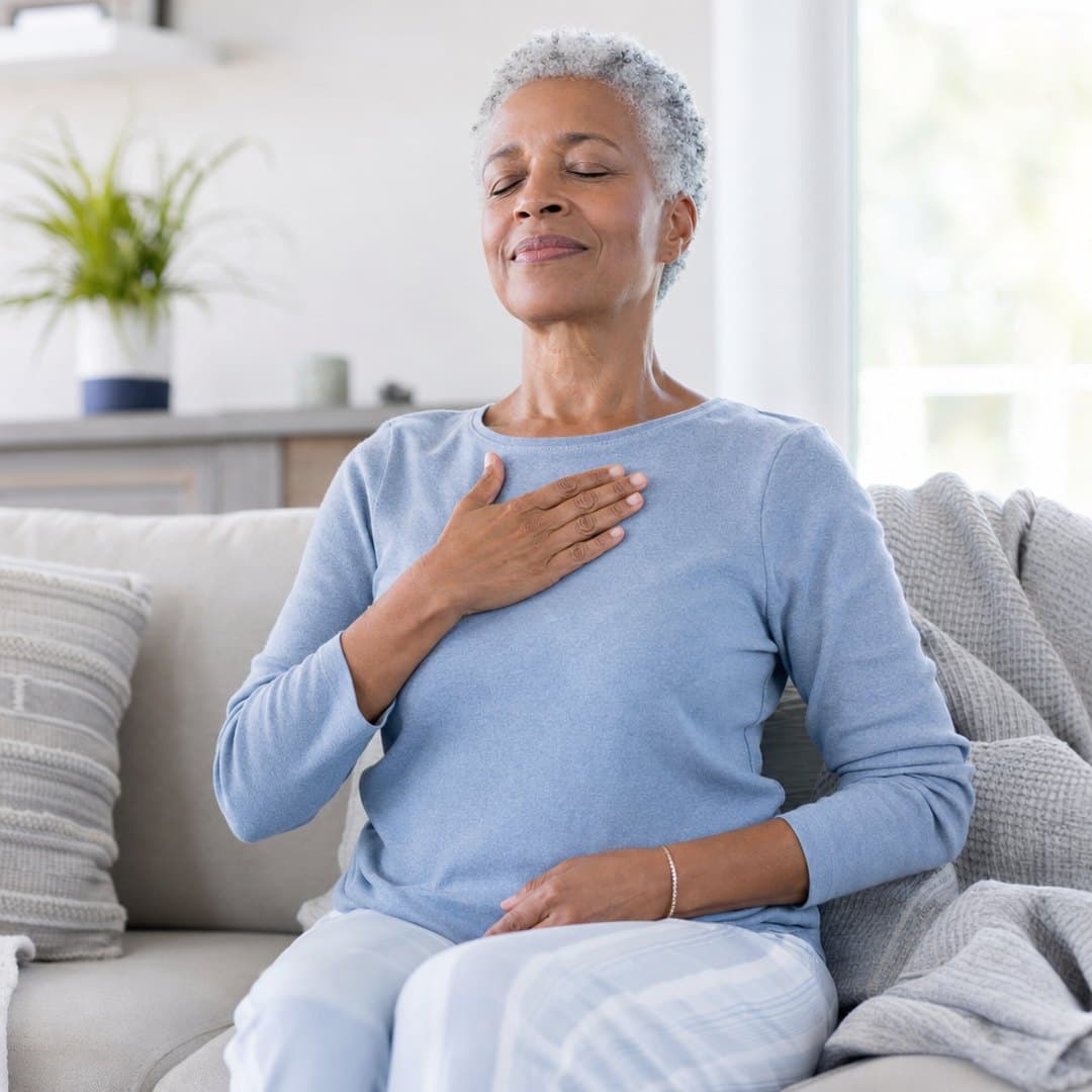 An older woman doing a calm guided breathing exercise at home